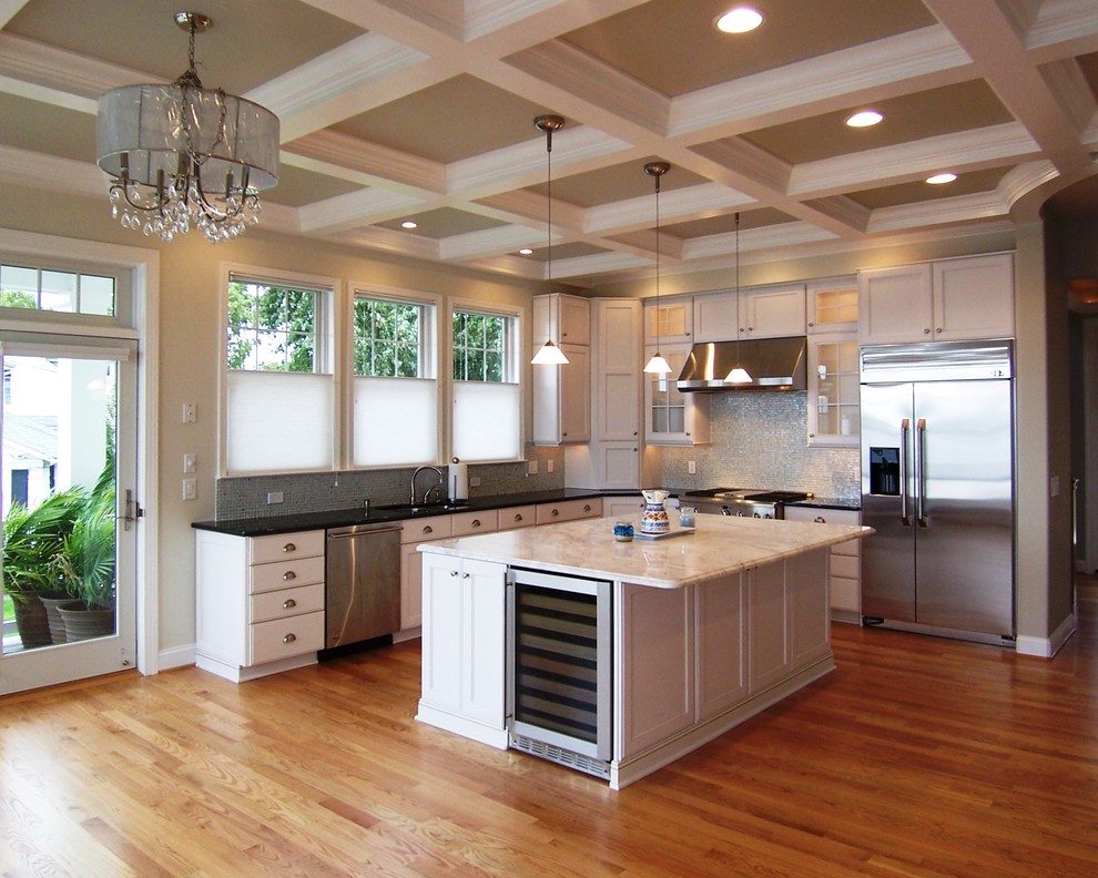 Mid-sized elegant l-shaped medium tone wood floor open concept kitchen photo in Baltimore with stainless steel appliances, white cabinets, mosaic tile backsplash, shaker cabinets, quartz countertops, an undermount sink, white backsplash and an island