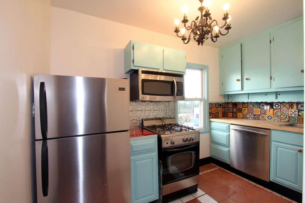 Small tuscan l-shaped terra-cotta tile enclosed kitchen photo in New York with a drop-in sink, flat-panel cabinets, blue cabinets, wood countertops, ceramic backsplash, stainless steel appliances and no island