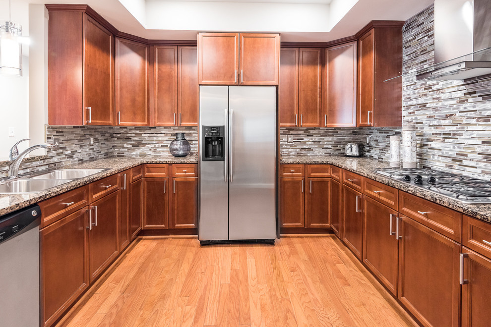 Exempel på ett mellanstort modernt u-kök, med en nedsänkt diskho, luckor med infälld panel, skåp i mellenmörkt trä, granitbänkskiva, flerfärgad stänkskydd, stänkskydd i stickkakel, rostfria vitvaror, ljust trägolv och brunt golv