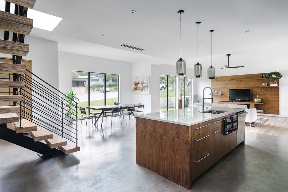 Inredning av ett modernt stort kök, med en undermonterad diskho, släta luckor, skåp i mellenmörkt trä, marmorbänkskiva, blått stänkskydd, stänkskydd i stenkakel, rostfria vitvaror, betonggolv, en köksö och grått golv