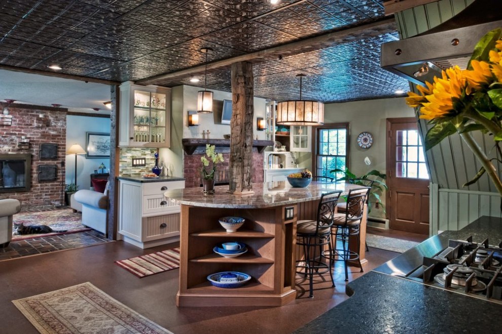 Inredning av ett lantligt stort kök, med en rustik diskho, luckor med profilerade fronter, vita skåp, granitbänkskiva, grönt stänkskydd, stänkskydd i stickkakel, rostfria vitvaror, mellanmörkt trägolv, en köksö och brunt golv