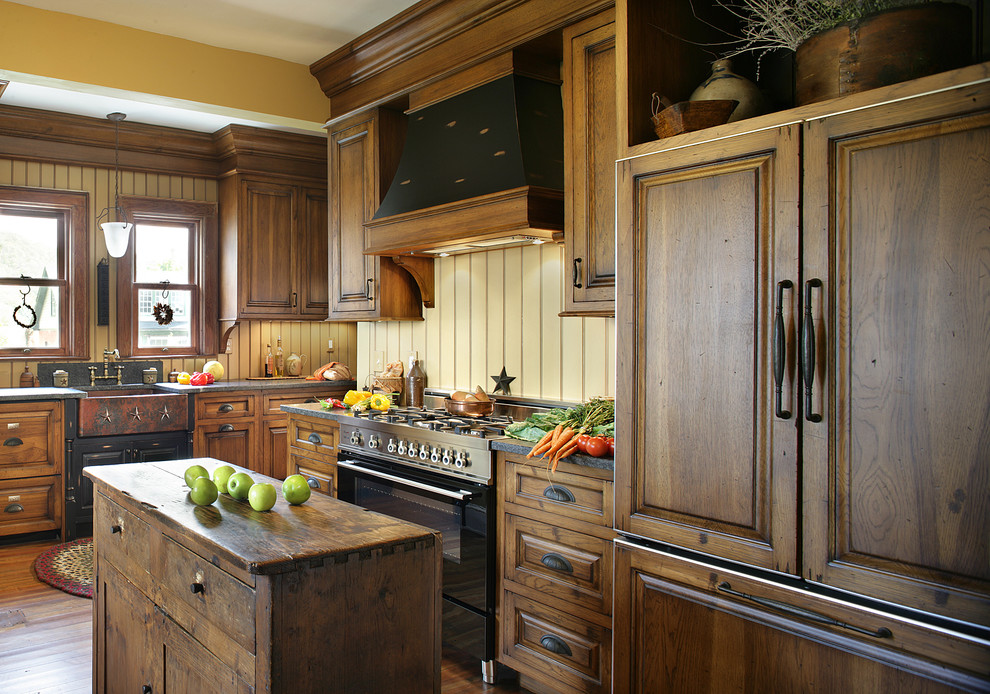 Immagine di un cucina con isola centrale rustico con lavello stile country, elettrodomestici da incasso, pavimento in legno massello medio, ante con bugna sagomata e ante in legno scuro