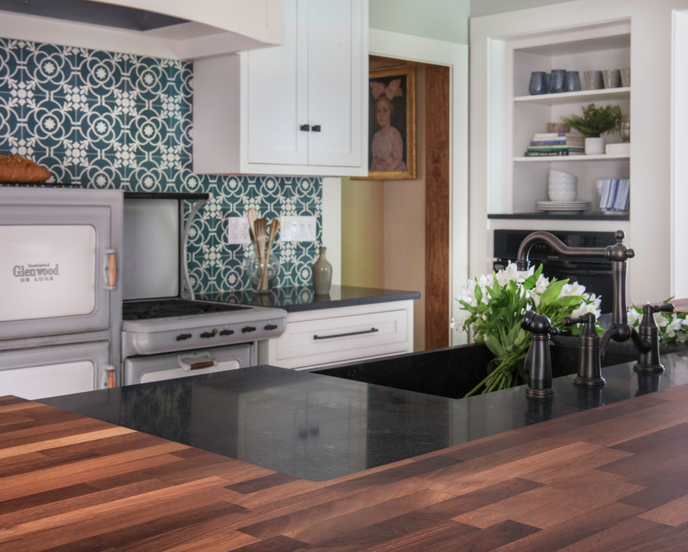 Exempel på ett mellanstort rustikt svart svart kök, med en rustik diskho, luckor med profilerade fronter, vita skåp, träbänkskiva, blått stänkskydd, stänkskydd i cementkakel, integrerade vitvaror, mellanmörkt trägolv, en köksö och brunt golv