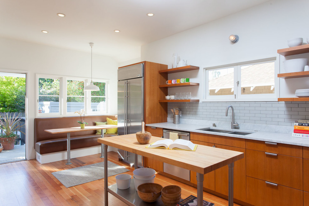 Klassische Wohnküche mit Doppelwaschbecken, flächenbündigen Schrankfronten, hellbraunen Holzschränken, Küchenrückwand in Weiß, Rückwand aus Metrofliesen, braunem Holzboden und Kücheninsel in San Francisco