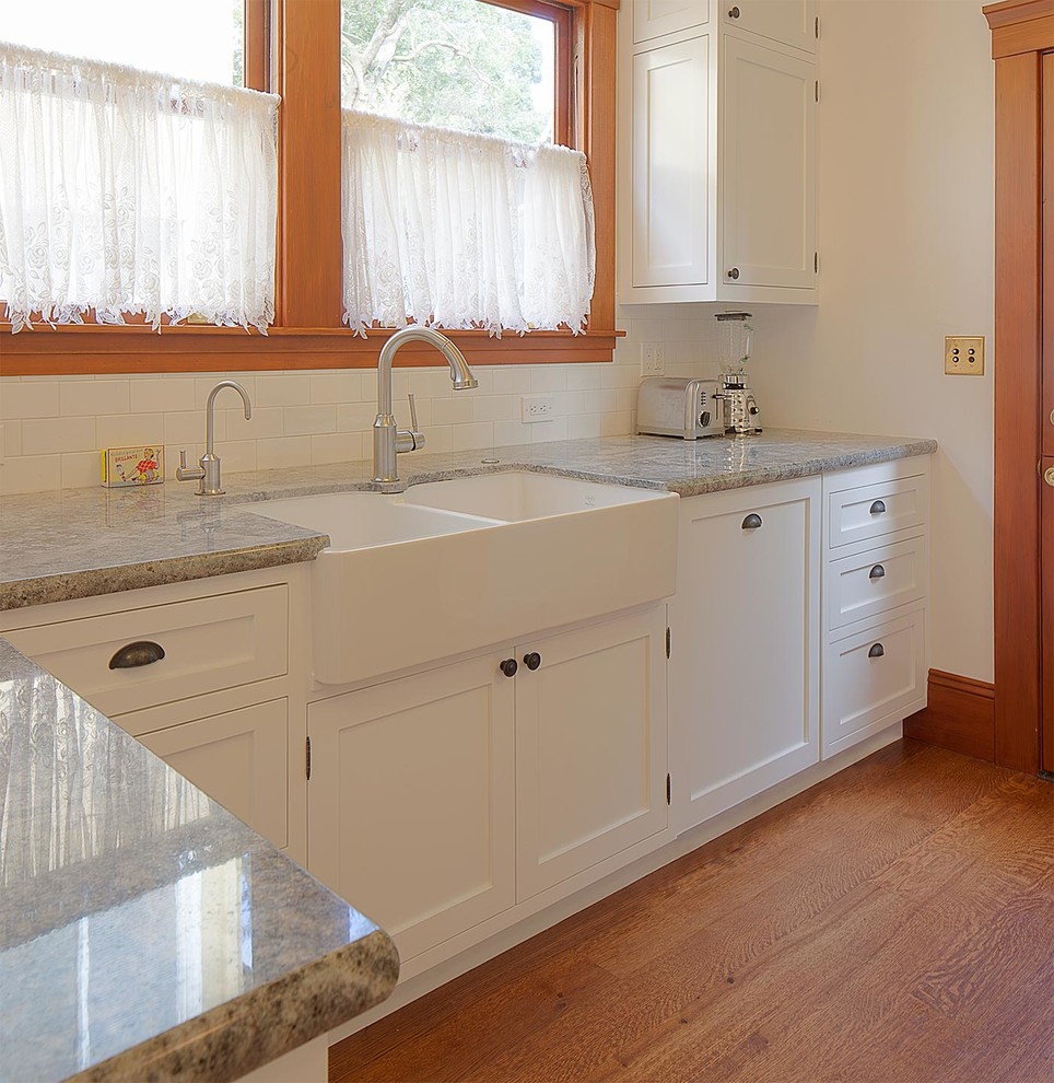 Foto på ett stort, avskilt amerikanskt u-kök, med en rustik diskho, skåp i shakerstil, vita skåp, granitbänkskiva, vitt stänkskydd, stänkskydd i keramik, integrerade vitvaror, en halv köksö och mellanmörkt trägolv