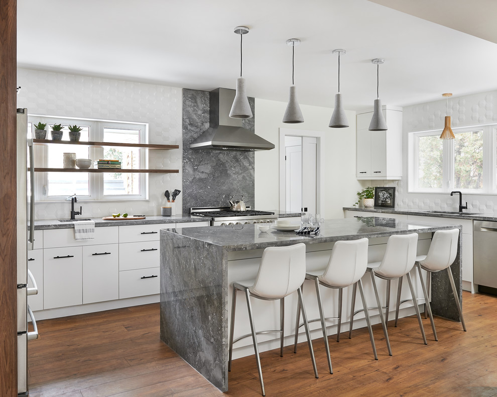 Example of a trendy u-shaped medium tone wood floor and brown floor eat-in kitchen design in Toronto with an undermount sink, flat-panel cabinets, white cabinets, white backsplash, stainless steel appliances, an island and gray countertops