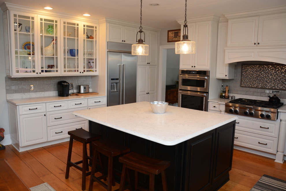 Idéer för att renovera ett stort vintage vit vitt kök, med en rustik diskho, luckor med upphöjd panel, vita skåp, bänkskiva i kvarts, grått stänkskydd, rostfria vitvaror, mellanmörkt trägolv, en köksö och brunt golv