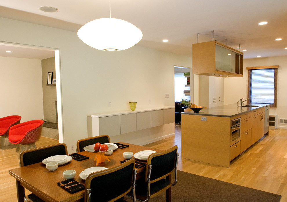 Пример оригинального дизайна: кухня в стиле модернизм с обеденным столом, плоскими фасадами и фасадами цвета дерева среднего тона