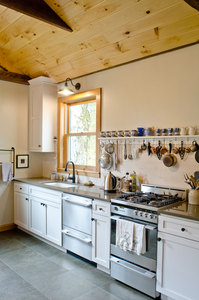 Inspiration for a medium sized rural galley enclosed kitchen in Minneapolis with a submerged sink, shaker cabinets, white cabinets, engineered stone countertops, white splashback, metro tiled splashback, stainless steel appliances, porcelain flooring and no island.