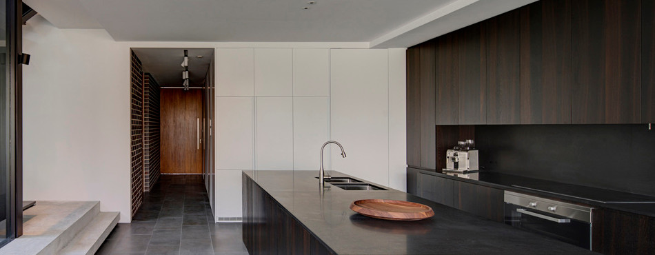 Zweizeilige, Mittelgroße Moderne Küche mit Kücheninsel, Unterbauwaschbecken, dunklen Holzschränken, Granit-Arbeitsplatte, Küchenrückwand in Schwarz, Vorratsschrank, Rückwand aus Stein und Küchengeräten aus Edelstahl in Sydney