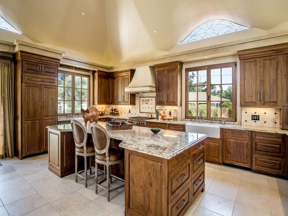 Inspiration for a large mediterranean u-shaped ceramic tile and beige floor enclosed kitchen remodel in Other with a farmhouse sink, raised-panel cabinets, dark wood cabinets, granite countertops, beige backsplash, ceramic backsplash, stainless steel appliances and an island