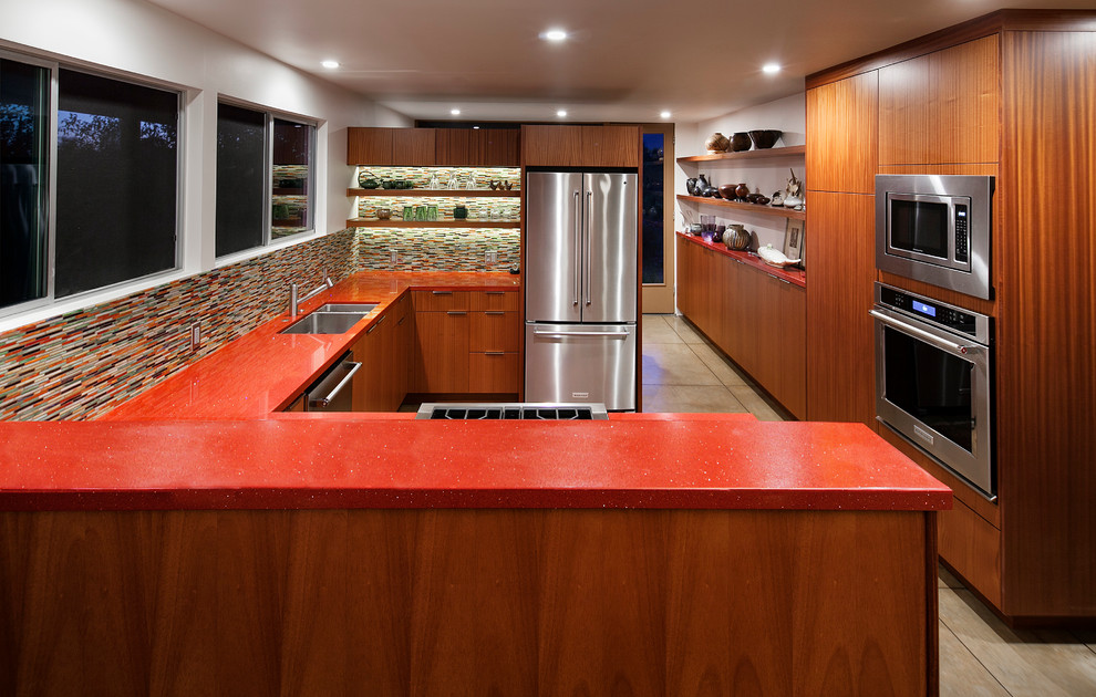Idéer för ett mellanstort 50 tals röd kök, med en undermonterad diskho, släta luckor, skåp i mellenmörkt trä, bänkskiva i kvarts, flerfärgad stänkskydd, stänkskydd i glaskakel, rostfria vitvaror och en halv köksö