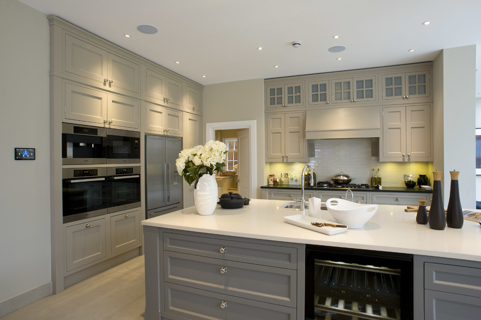 ロンドンにあるトランジショナルスタイルのおしゃれなキッチン (アンダーカウンターシンク、落し込みパネル扉のキャビネット、グレーのキャビネット、白いキッチンパネル、シルバーの調理設備) の写真
