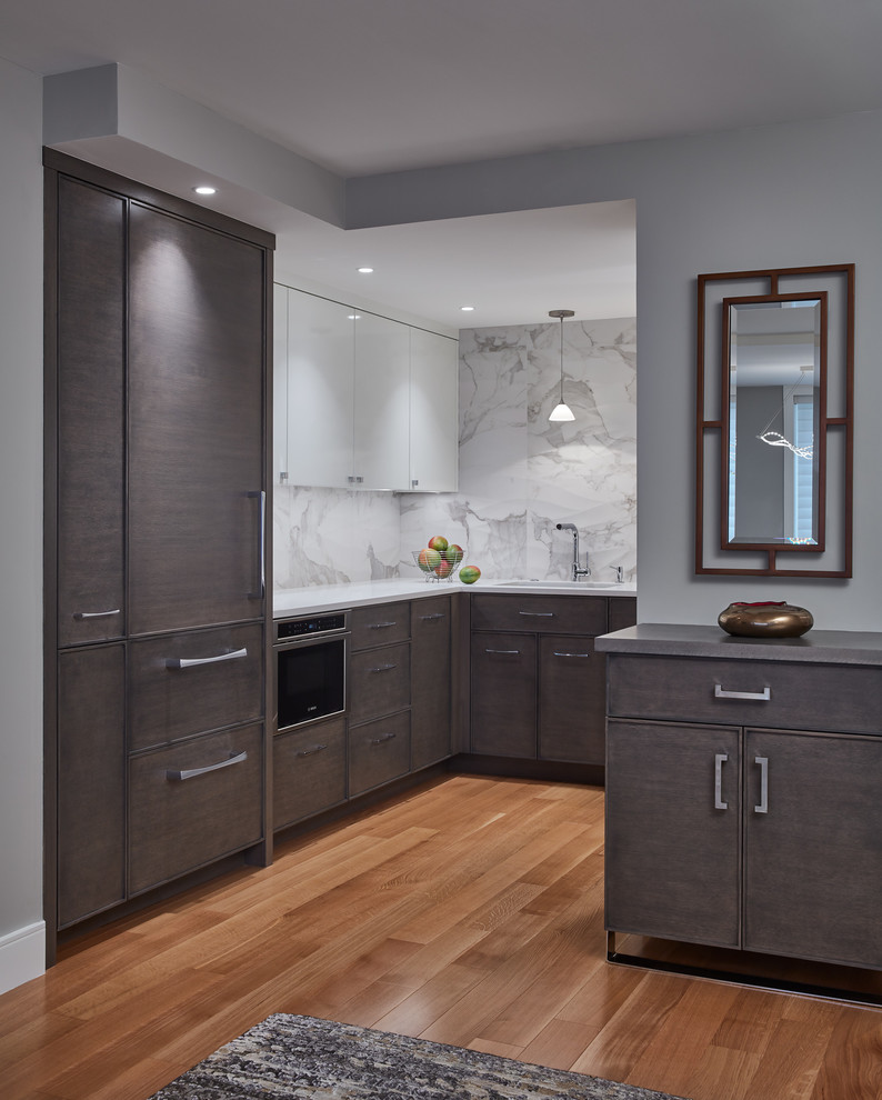 Small minimalist u-shaped light wood floor and brown floor enclosed kitchen photo in Boston with an undermount sink, flat-panel cabinets, dark wood cabinets, solid surface countertops, white backsplash, marble backsplash, stainless steel appliances and no island