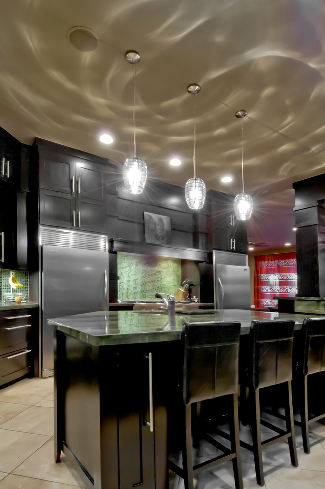 Inspiration för ett stort funkis kök, med en undermonterad diskho, luckor med infälld panel, svarta skåp, granitbänkskiva, grönt stänkskydd, stänkskydd i glaskakel, rostfria vitvaror, travertin golv och flera köksöar