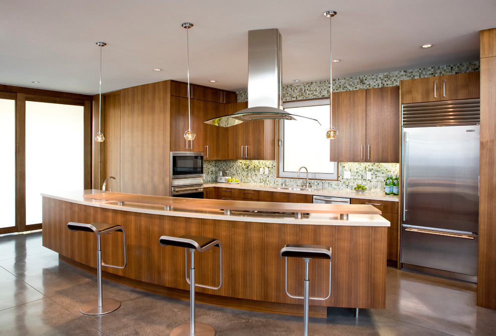 Modern inredning av ett kök, med släta luckor, stänkskydd i mosaik, rostfria vitvaror, grönt stänkskydd och skåp i mörkt trä