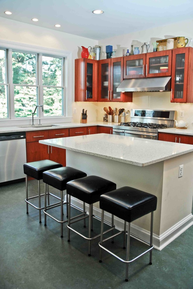 Photo of a medium sized contemporary l-shaped enclosed kitchen in Baltimore with a built-in sink, glass-front cabinets, medium wood cabinets, composite countertops, stainless steel appliances, slate flooring and an island.