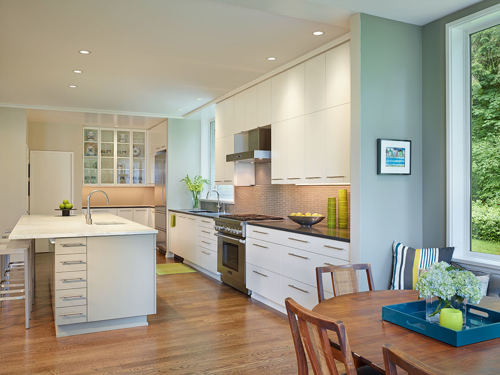 Cette photo montre une cuisine linéaire tendance avec un placard à porte plane, des portes de placard blanches, un électroménager en acier inoxydable et une crédence beige.