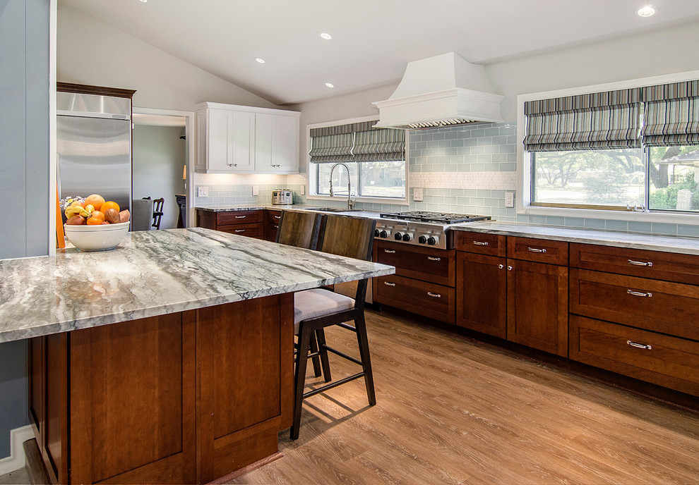 Eat-in kitchen - mid-sized traditional u-shaped vinyl floor eat-in kitchen idea in Dallas with an undermount sink, shaker cabinets, medium tone wood cabinets, quartzite countertops, blue backsplash, glass tile backsplash, stainless steel appliances and an island