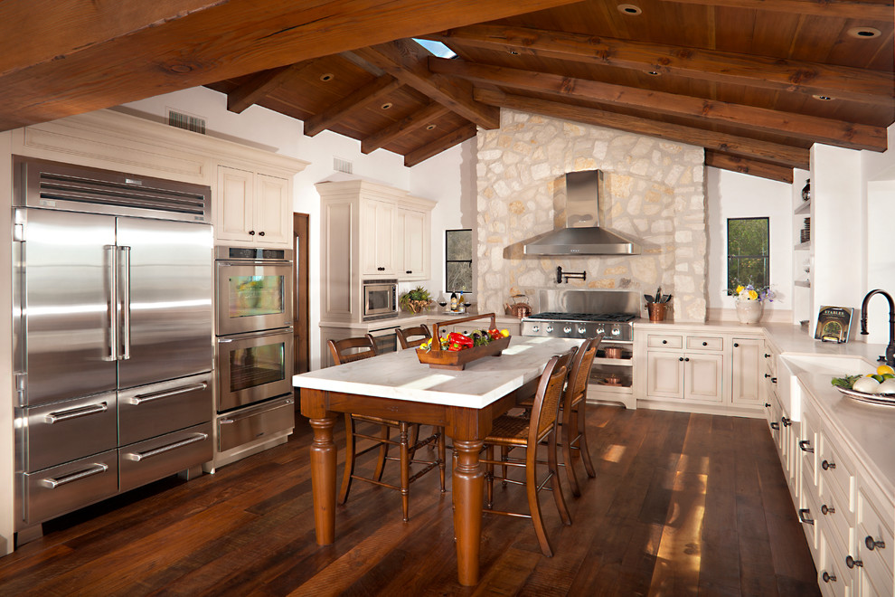 Exempel på ett stort medelhavsstil kök, med en rustik diskho, bänkskiva i kalksten, rostfria vitvaror, mörkt trägolv och en köksö