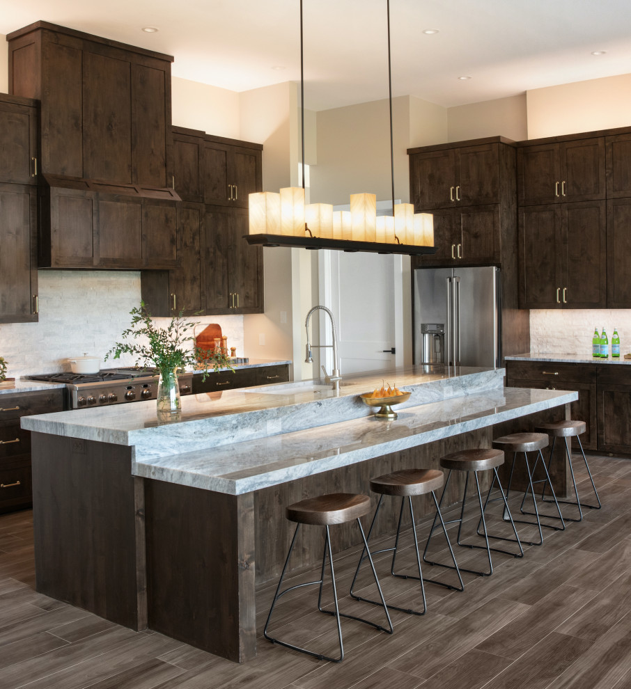 Design ideas for a large classic galley kitchen in Austin with a submerged sink, shaker cabinets, dark wood cabinets, granite worktops, grey splashback, stone tiled splashback, stainless steel appliances, porcelain flooring, an island, brown floors and grey worktops.