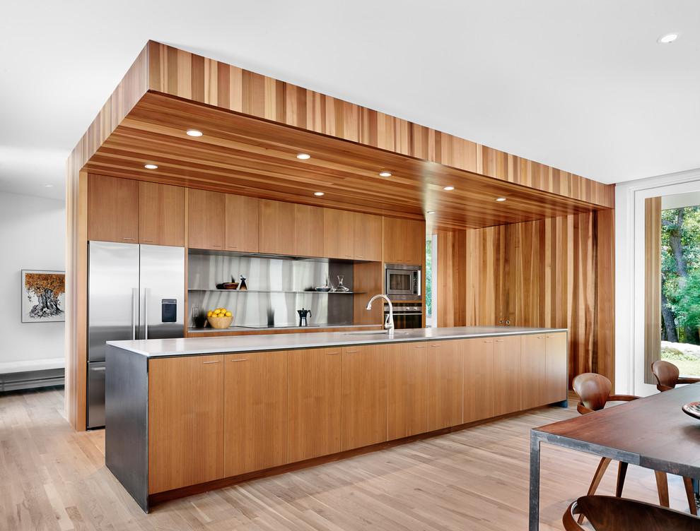 На фото: большая параллельная кухня-гостиная в современном стиле с плоскими фасадами, фасадами цвета дерева среднего тона и островом
