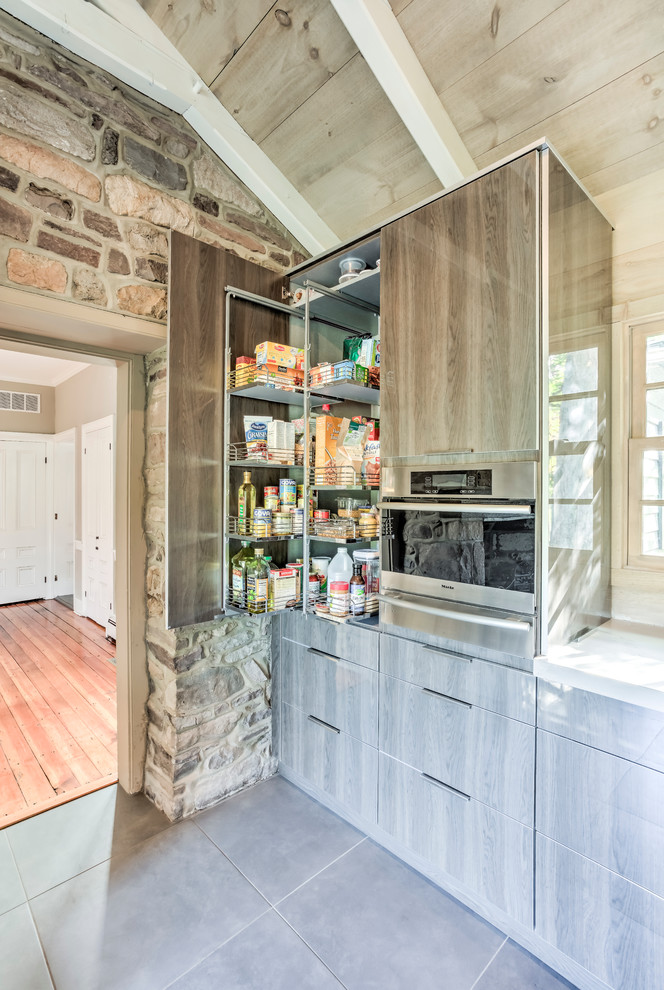 Rustik inredning av ett stort linjärt kök och matrum, med en undermonterad diskho, släta luckor, grå skåp, bänkskiva i kvartsit, integrerade vitvaror, skiffergolv och en köksö
