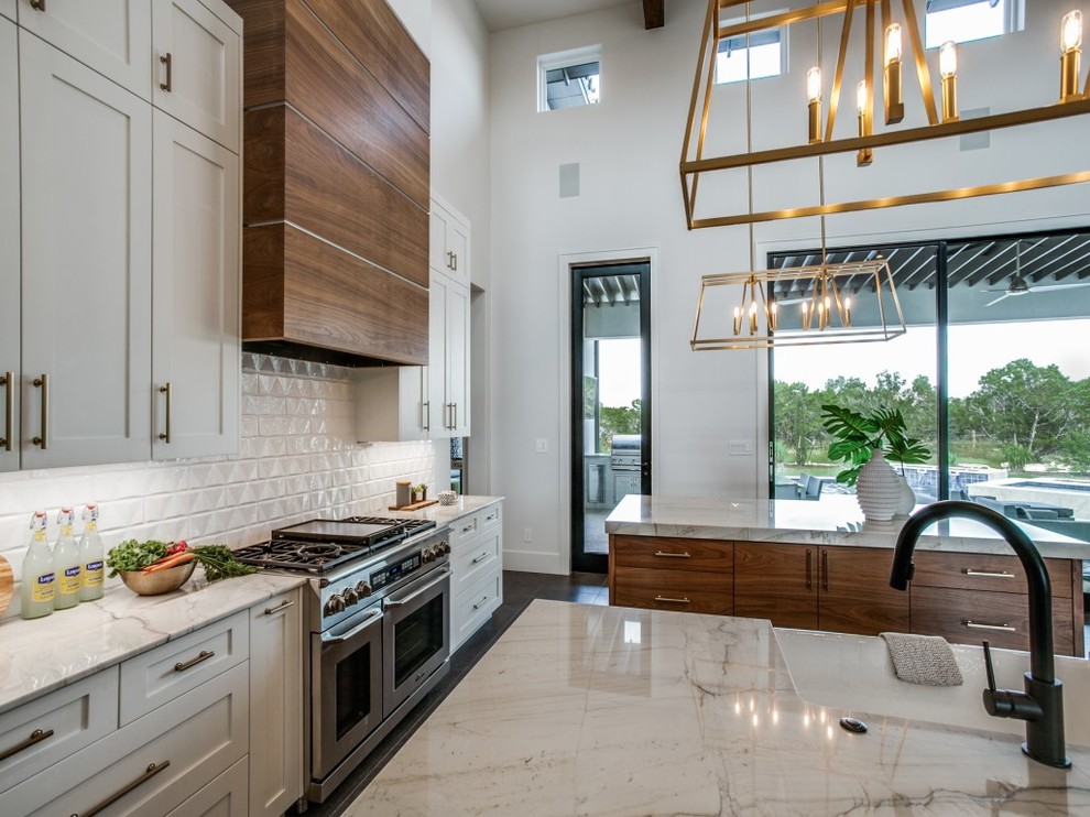 Large farmhouse u-shaped porcelain tile and gray floor open concept kitchen photo in Houston with a farmhouse sink, shaker cabinets, white cabinets, quartzite countertops, white backsplash, subway tile backsplash, stainless steel appliances, two islands and white countertops