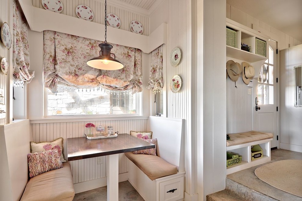 Exemple d'une cuisine américaine romantique avec des portes de placard blanches et sol en béton ciré.