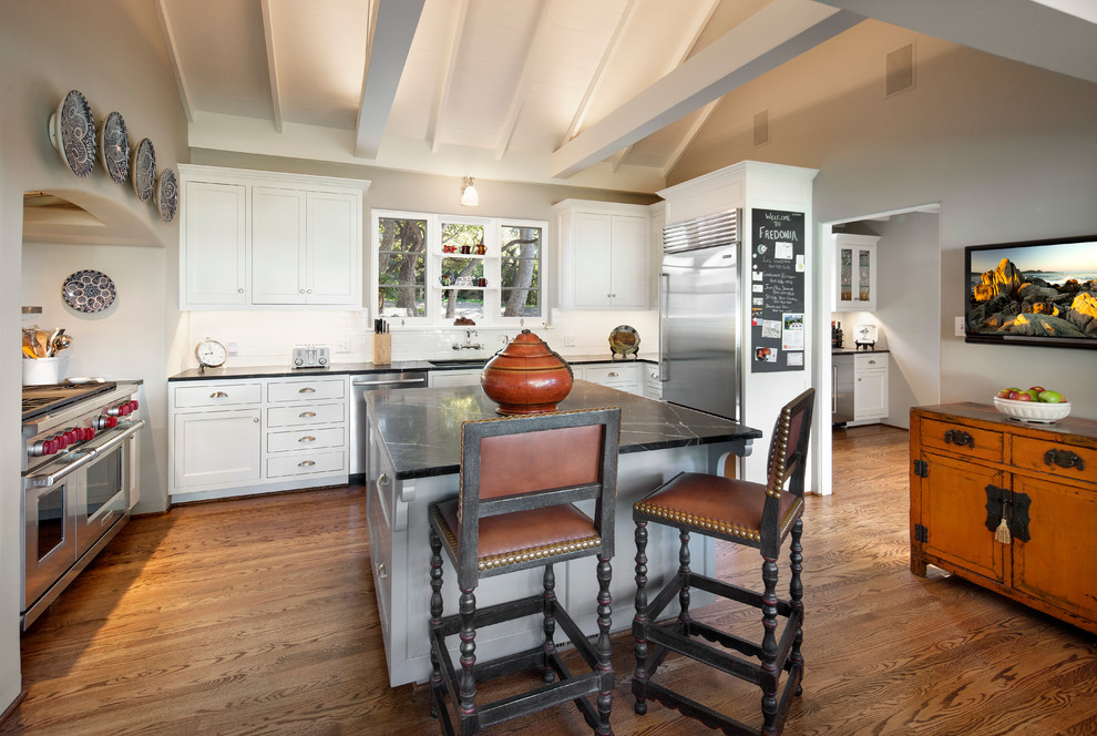 Klassische Küche mit Schrankfronten im Shaker-Stil, weißen Schränken, Küchenrückwand in Weiß, Küchengeräten aus Edelstahl, dunklem Holzboden und Kücheninsel in Santa Barbara