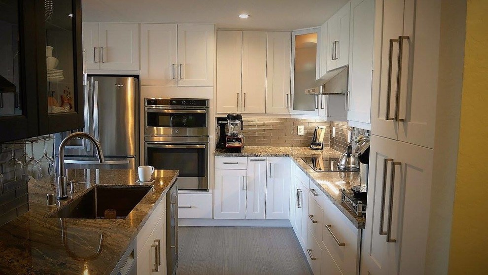 Example of a small trendy galley ceramic tile and gray floor open concept kitchen design in San Francisco with an undermount sink, shaker cabinets, white cabinets, granite countertops, brown backsplash, glass tile backsplash, stainless steel appliances and an island