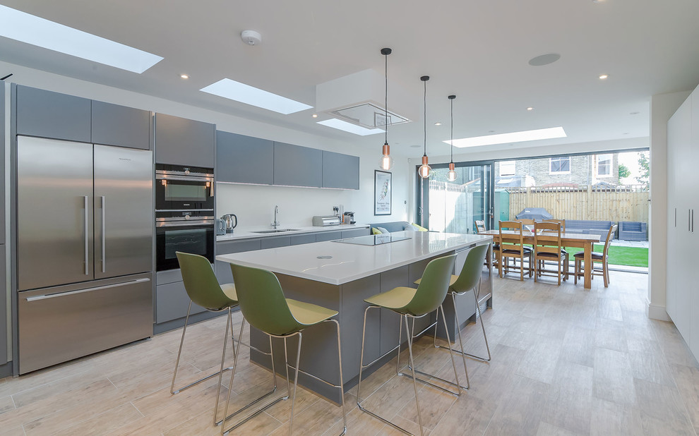Inspiration for a medium sized contemporary single-wall kitchen/diner in London with a submerged sink, flat-panel cabinets, grey cabinets, stainless steel appliances, an island, beige floors and white worktops.