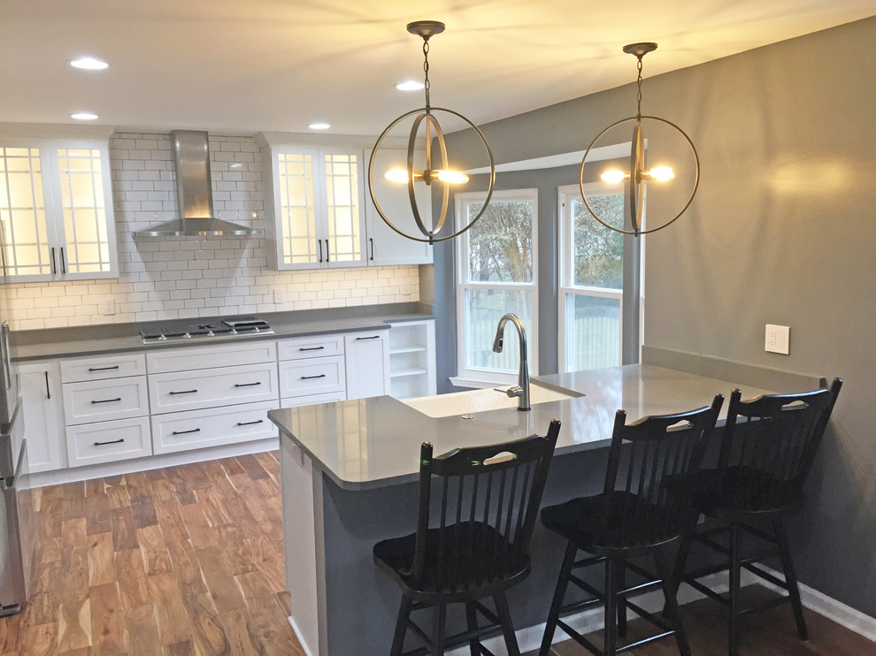 Exempel på ett stort klassiskt grå grått kök, med en rustik diskho, skåp i shakerstil, vita skåp, bänkskiva i kvarts, vitt stänkskydd, stänkskydd i keramik, rostfria vitvaror, mellanmörkt trägolv, en halv köksö och brunt golv