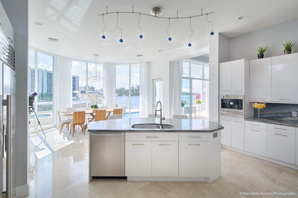This is an example of a coastal u-shaped kitchen pantry in Boston with flat-panel cabinets, white cabinets, granite worktops, grey splashback, metal splashback, stainless steel appliances, cement flooring, an island and beige floors.