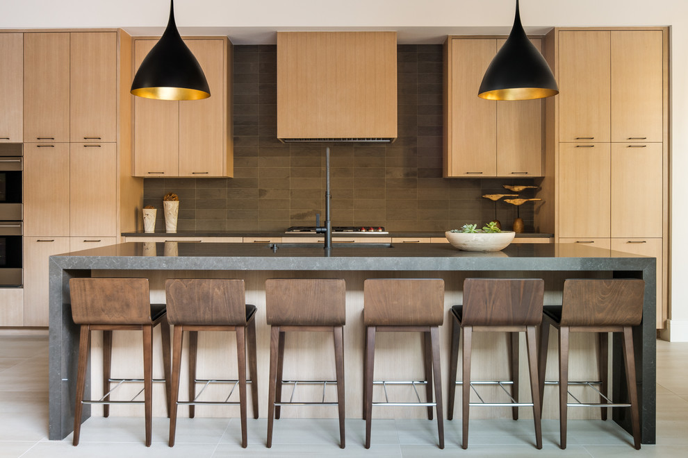 Foto de cocina contemporánea con armarios con paneles lisos, puertas de armario de madera clara, salpicadero marrón, electrodomésticos de acero inoxidable, una isla, suelo gris y encimeras grises