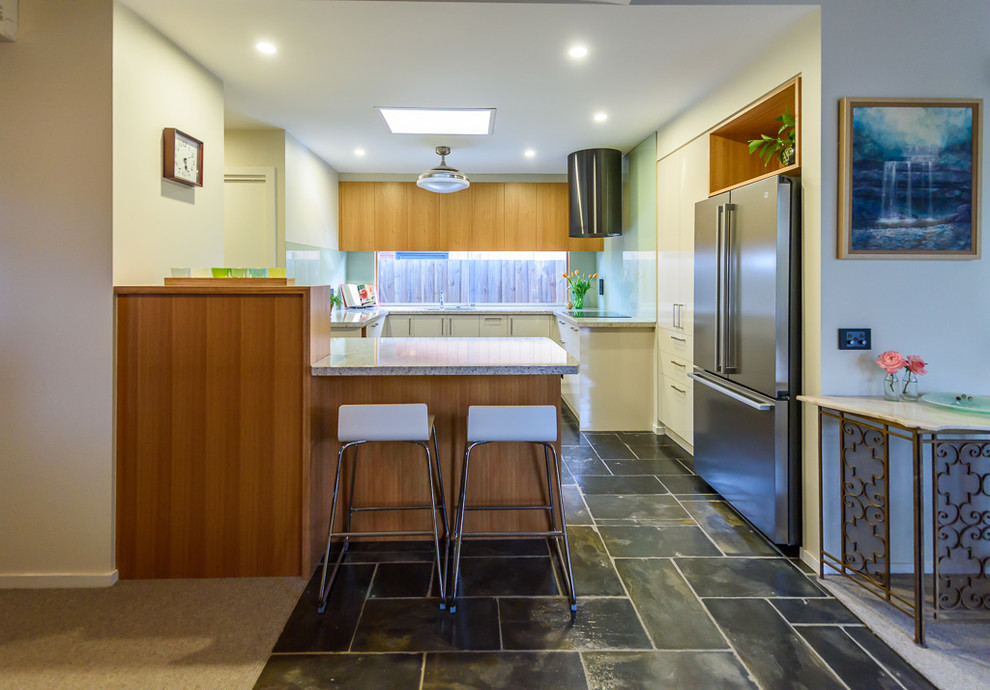 Esempio di una cucina moderna di medie dimensioni con lavello da incasso, ante lisce, ante in legno chiaro, top in laminato, paraspruzzi blu, paraspruzzi con piastrelle di vetro, elettrodomestici neri, pavimento in ardesia e penisola