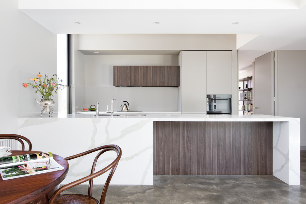 Offene, Zweizeilige, Mittelgroße Moderne Küche mit dunklen Holzschränken, Marmor-Arbeitsplatte, Küchenrückwand in Grau, Glasrückwand, Betonboden, Kücheninsel, grauem Boden, weißer Arbeitsplatte und gewölbter Decke in Melbourne