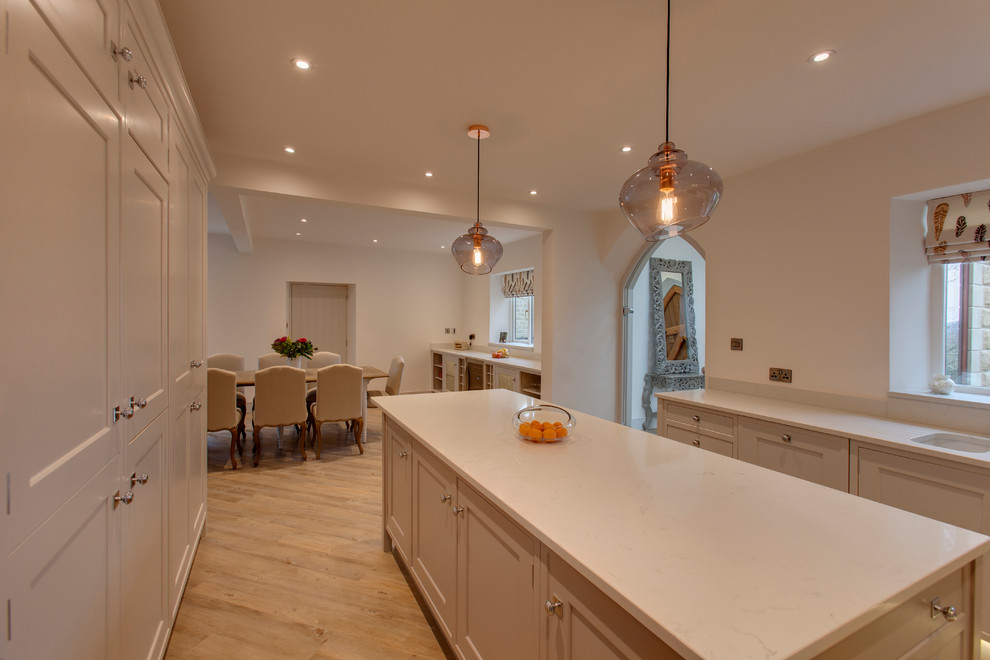Inspiration for a large classic u-shaped open plan kitchen in Other with a double-bowl sink, beaded cabinets, white cabinets, quartz worktops, white splashback, stainless steel appliances, light hardwood flooring and an island.
