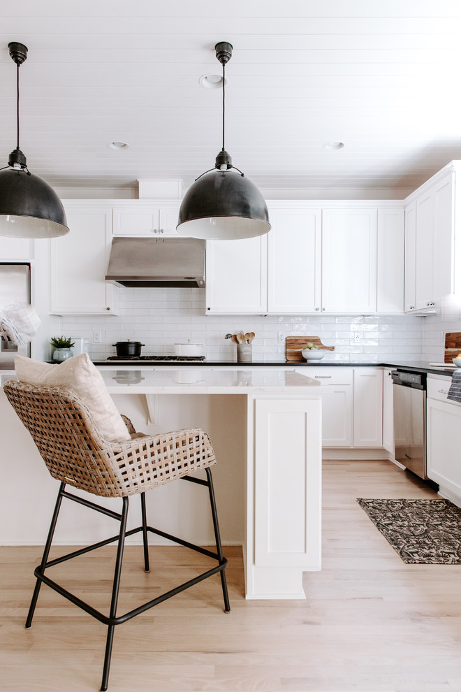 Foto på ett mellanstort lantligt vit kök, med en undermonterad diskho, skåp i shakerstil, vita skåp, bänkskiva i kvarts, vitt stänkskydd, stänkskydd i keramik, rostfria vitvaror, ljust trägolv, en köksö och beiget golv