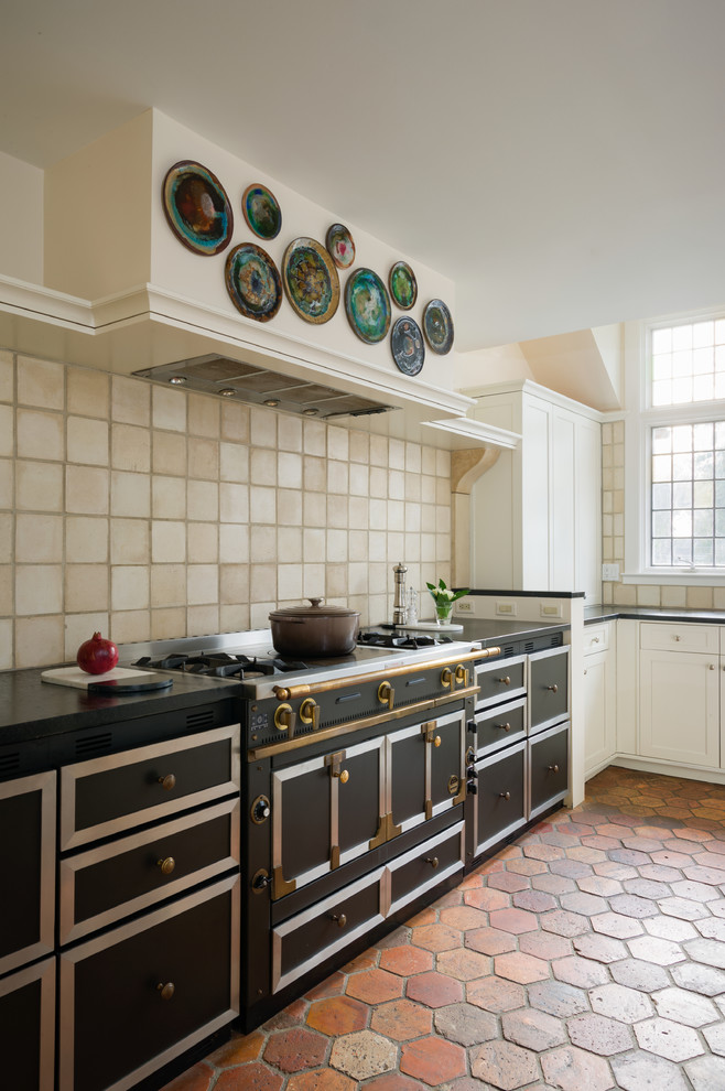 Exempel på ett avskilt, stort klassiskt l-kök, med en undermonterad diskho, skåp i shakerstil, vita skåp, träbänkskiva, beige stänkskydd, stänkskydd i keramik, svarta vitvaror och klinkergolv i terrakotta