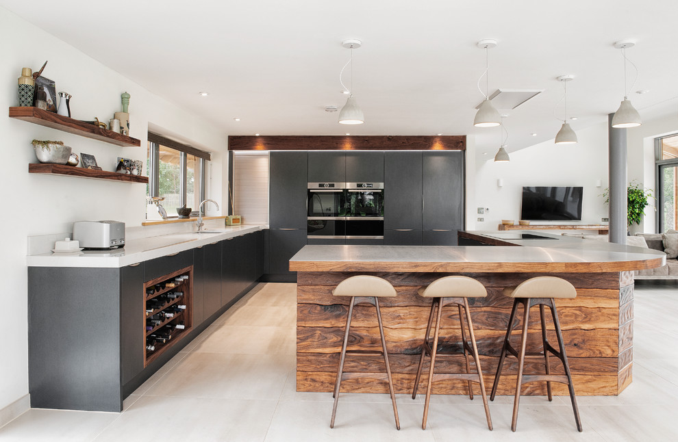 Photo of a medium sized contemporary l-shaped open plan kitchen in Other with flat-panel cabinets, black cabinets, white splashback, stainless steel appliances, light hardwood flooring and beige floors.
