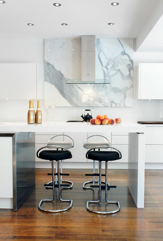 Inspiration for a contemporary kitchen in Toronto with flat-panel cabinets, white cabinets, engineered stone countertops, white splashback, glass sheet splashback, integrated appliances and medium hardwood flooring.