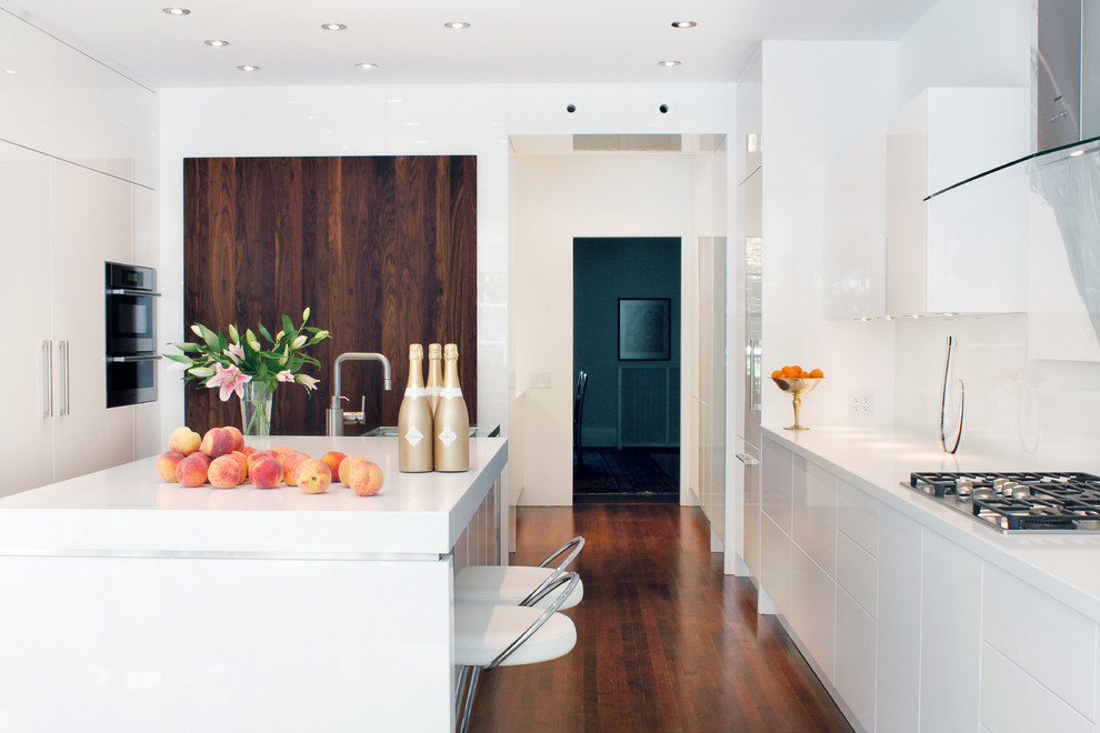 Photo of a contemporary kitchen in Toronto with flat-panel cabinets, white cabinets, engineered stone countertops, white splashback, glass sheet splashback, integrated appliances and medium hardwood flooring.