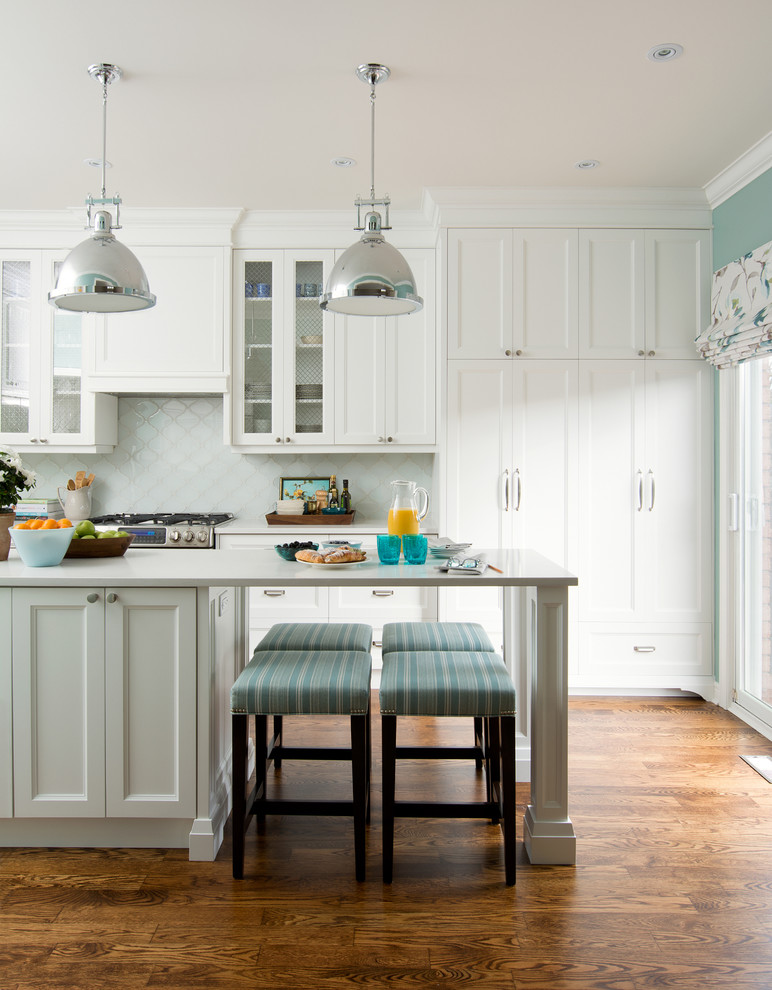 Example of a classic medium tone wood floor kitchen design in Toronto with shaker cabinets, white cabinets, quartz countertops and blue backsplash