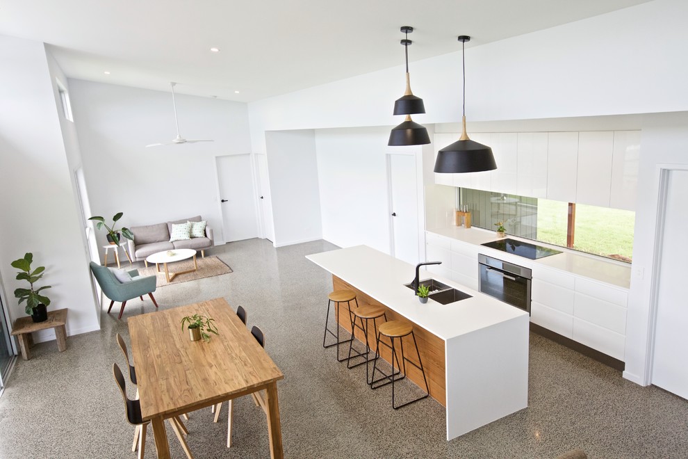 Inspiration för mellanstora moderna vitt kök, med rostfria vitvaror, en köksö, en undermonterad diskho, släta luckor, vita skåp, bänkskiva i kvarts, glaspanel som stänkskydd, betonggolv och grått golv