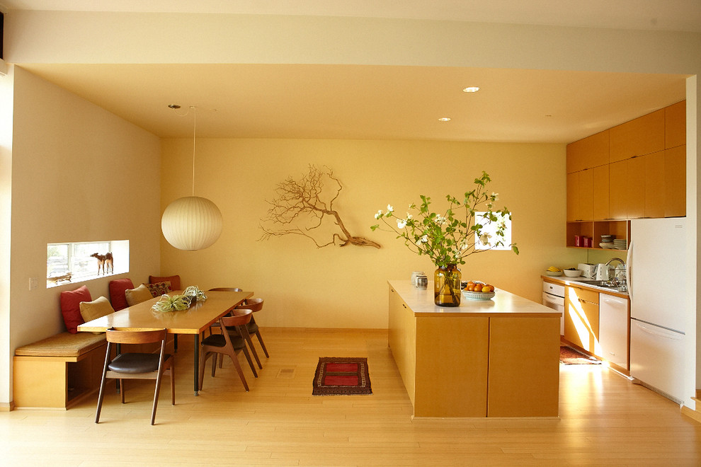 Example of a mid-century modern galley eat-in kitchen design in Los Angeles with white appliances, flat-panel cabinets and medium tone wood cabinets