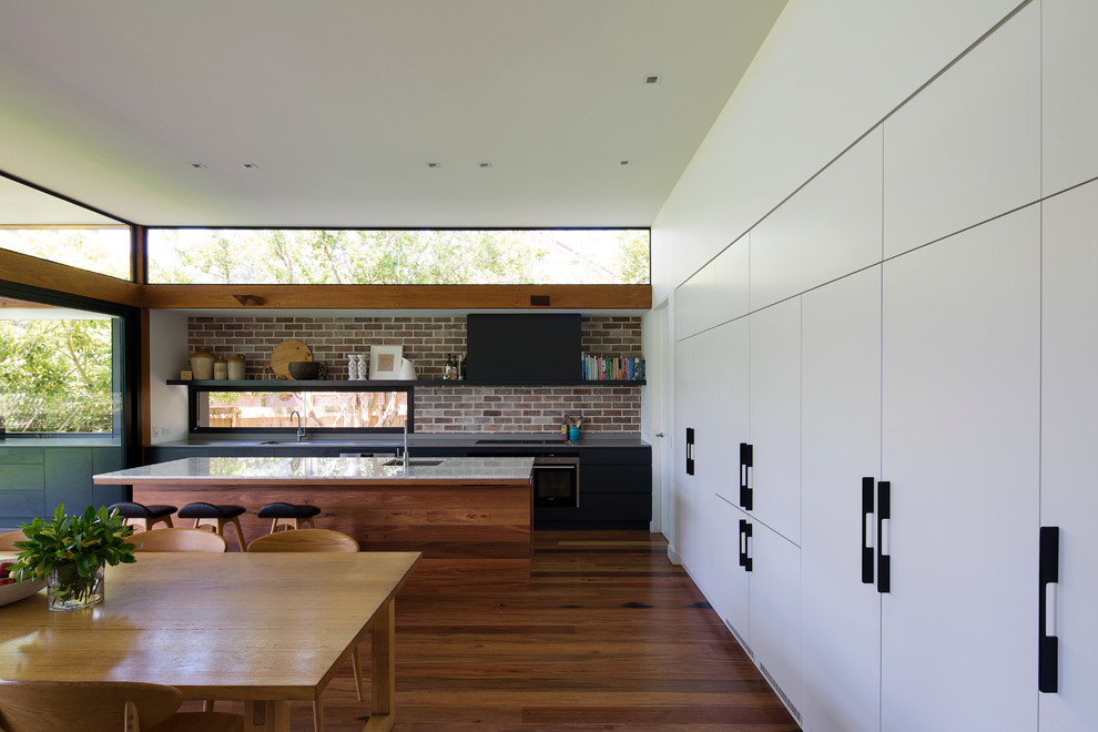 Modern inredning av ett stort kök, med en undermonterad diskho, marmorbänkskiva, rostfria vitvaror, mellanmörkt trägolv och en köksö