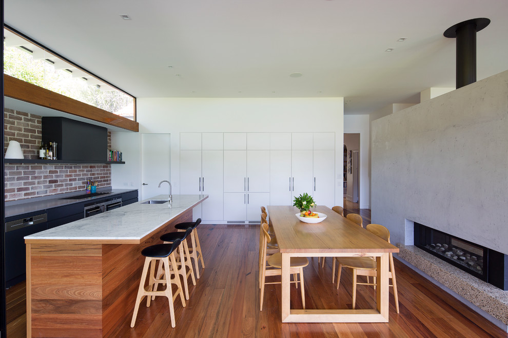 シドニーにあるコンテンポラリースタイルのおしゃれなアイランドキッチン (アンダーカウンターシンク、フラットパネル扉のキャビネット、サブウェイタイルのキッチンパネル、シルバーの調理設備、無垢フローリング、白いキャビネット) の写真