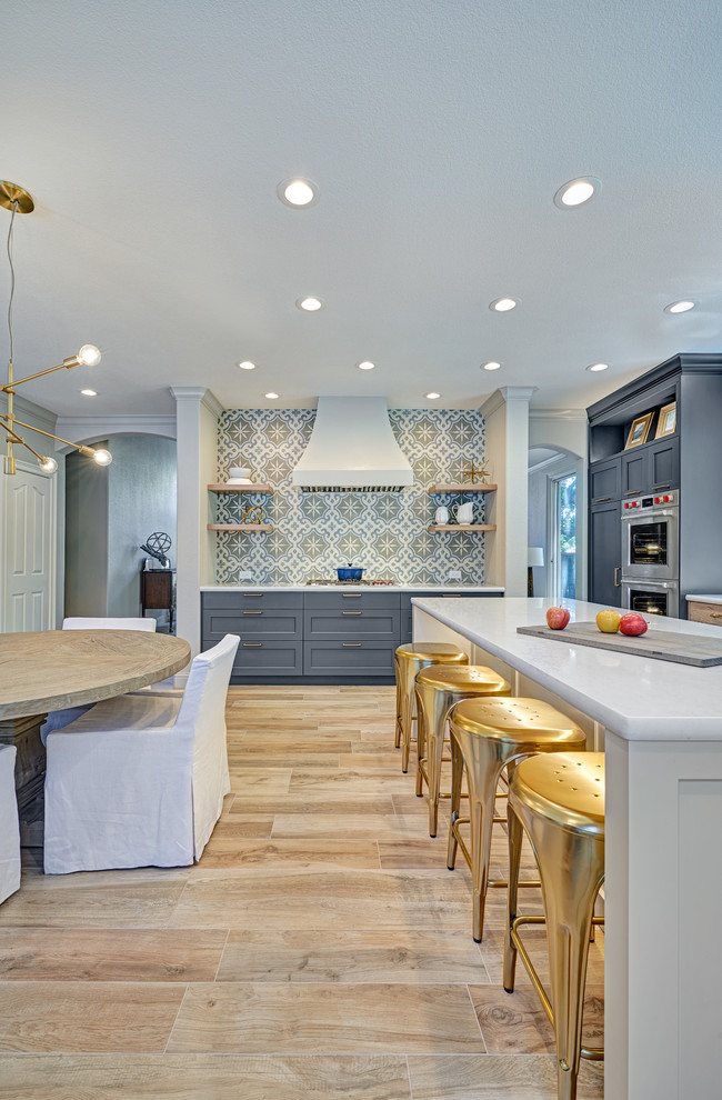 Large traditional l-shaped kitchen/diner in Sacramento with a submerged sink, recessed-panel cabinets, blue cabinets, engineered stone countertops, grey splashback, ceramic splashback, stainless steel appliances, porcelain flooring, an island, beige floors and white worktops.