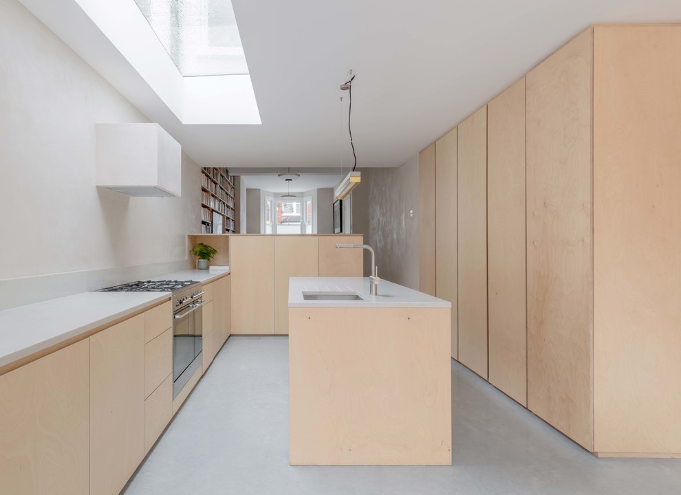 Inspiration for a scandi u-shaped kitchen in London with a submerged sink, flat-panel cabinets, light wood cabinets, white splashback, stainless steel appliances, concrete flooring, an island, grey floors and white worktops.